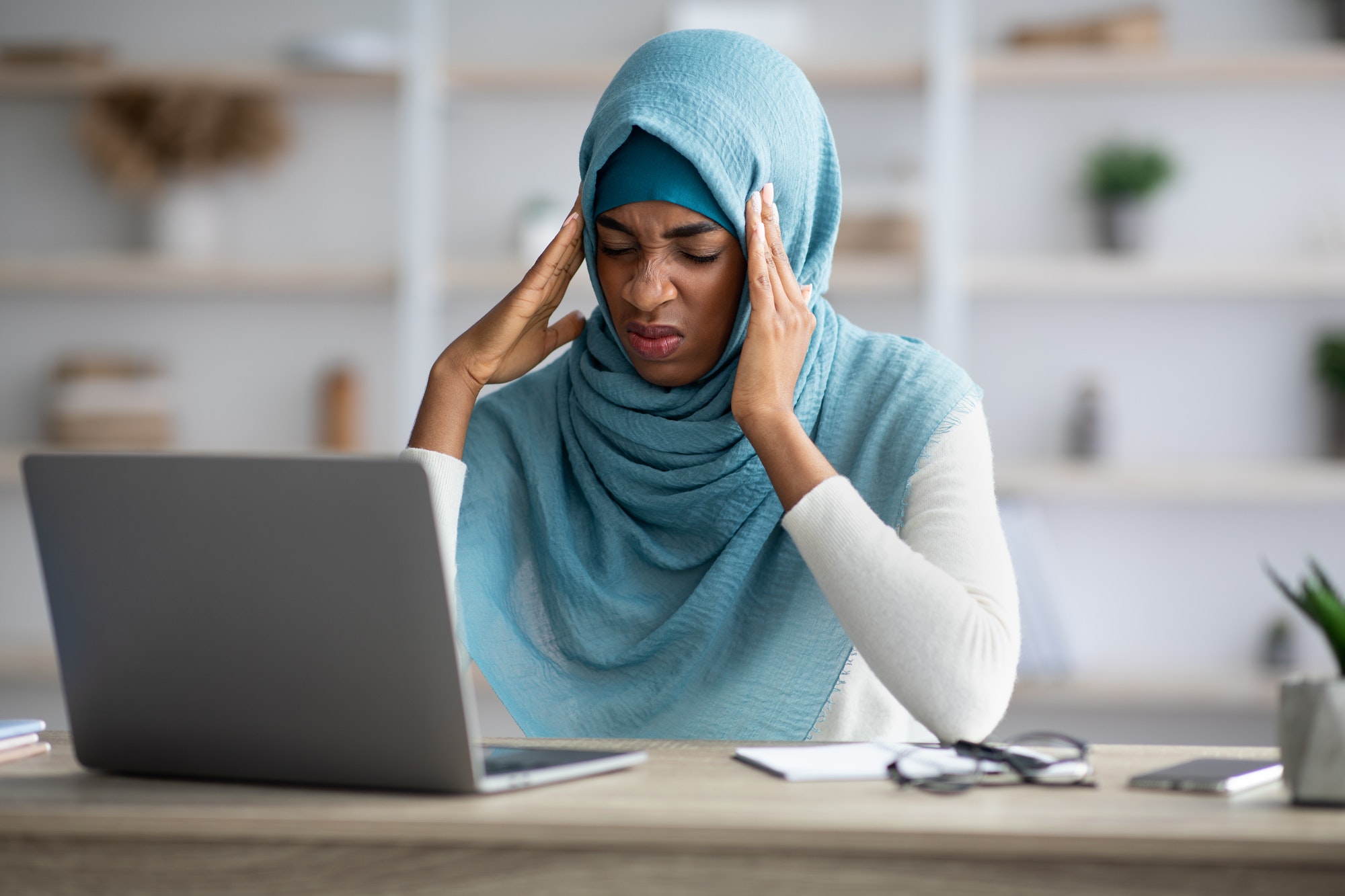 Headache Concept. Stressed Black Muslim Freelancer Lady Suffering From Migraine At Workplace